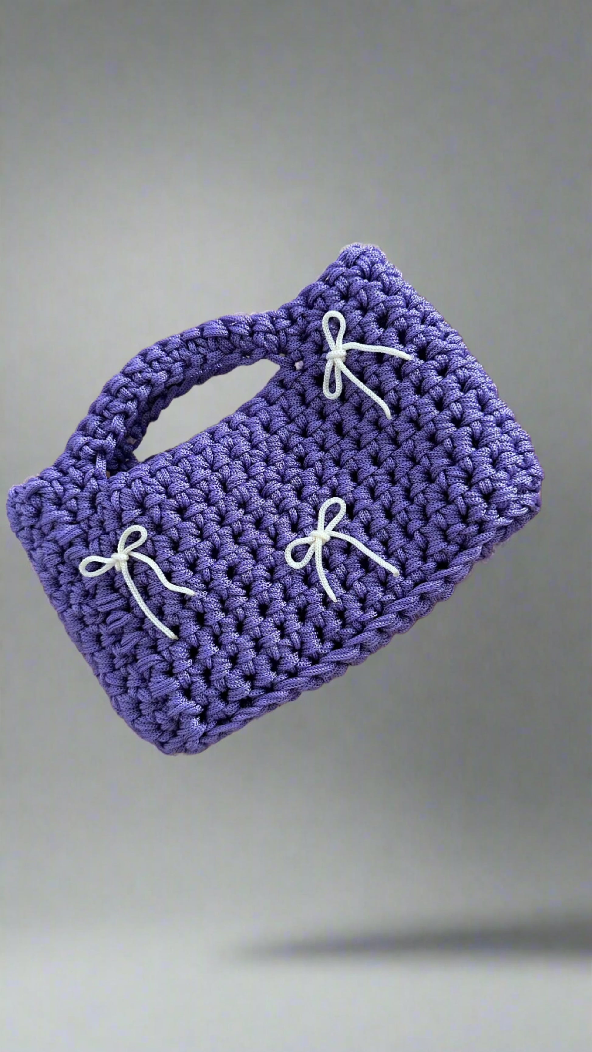 <img ="creaturina_bag.png" alt="Luglina mini bag uncinetto fatta a mano colore lilla con fiocchetti panna">