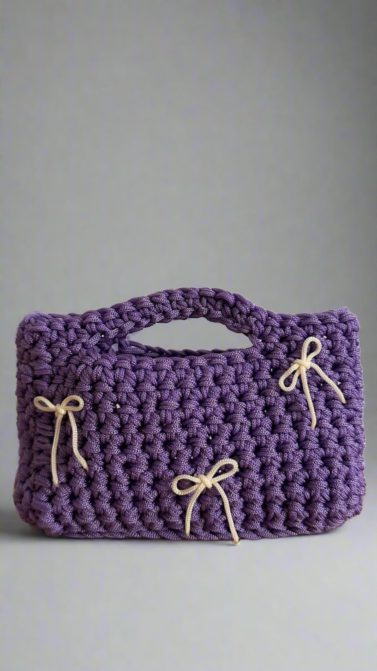 <img ="creaturina_bag.png" alt="Luglina mini bag uncinetto fatta a mano colore lilla con fiocchetti panna">